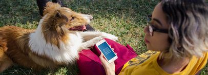 Mockup of an iPhone in Portrait Position Featuring a Woman Sitting in the Garden with Her Dog