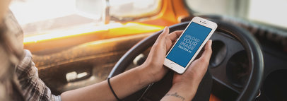 Mockup of a Woman Holding an iPhone in Portrait Position in the Driver's Seat 12933wide
