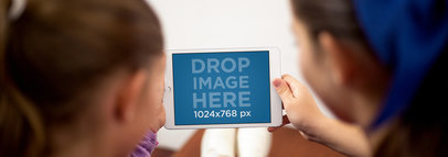 Mockup of Two Girls Holding an iPad in Landscape Position at Home