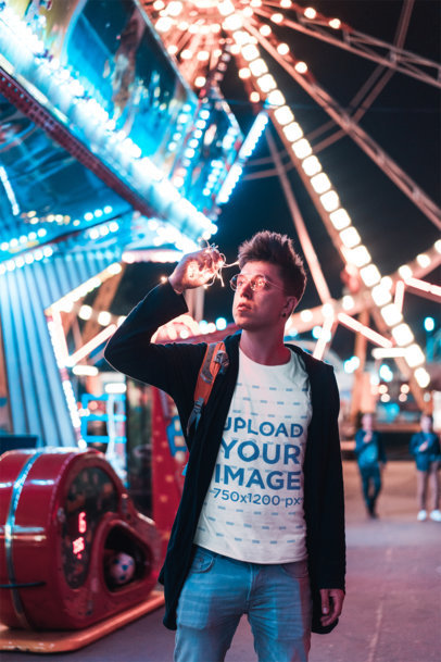 T-Shirt Mockup of a Man Against a Ferris Wheel at Night