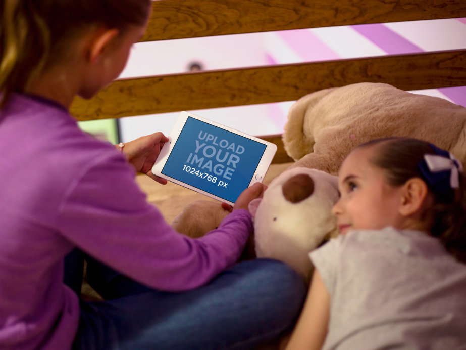 Young Girl Playing on her iPad Mini Mockup While her Little Sister Watches 