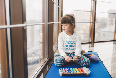Mockup of a Little Girl with a Long-Sleeve Tee Playing with a Xylophone
