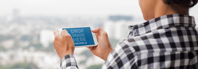Young Man Playing on his White iPhone 7 Plus Mockup in Landscape Position at his Apartment Balcony