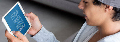 White iPad Mini Mockup of a Teenager Playing in Landscape Position in his Living Room