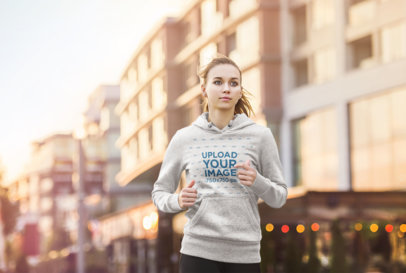Mockup of a Woman Wearing a Heathered Hoodie While Jogging 