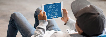 Mockup of a Man Lying on His Back Holding an iPad in Landscape Position