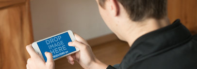 iPhone 7 Plus Mockup of a Teenage Boy Playing Indoors