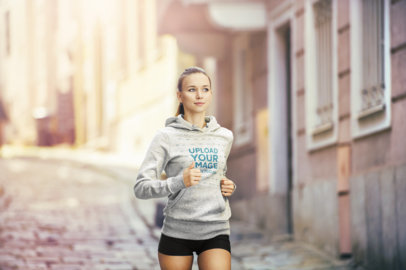 Pullover Hoodie Mockup of a Young Woman Jogging in the City
