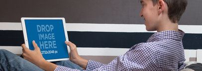 Young Boy Playing on his iPad Pro in Landscape Position Mockup at his House a13054wide
