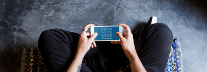 Tattooed Man Playing in his Room with a White iPhone 7 Plus in Landscape Position Mockup a13109w