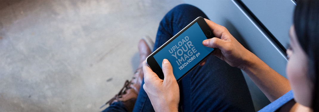 Black iPhone 7 Plus Mockup Held in Landscape Position by a Young Woman Playing a Video Game