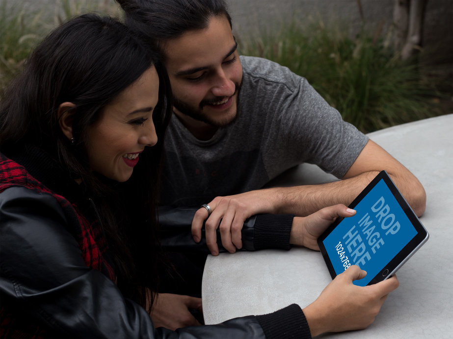Mockup of a Young Couple Using an iPad in Landscape Position at their Terrace