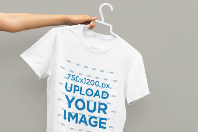 Mockup of a Person Holding a Hanger with a T-Shirt