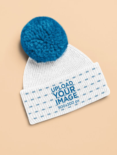 Mockup of a Pom-Pom Beanie Lying on a Colored Surface