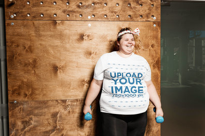 Mockup of a Woman with a Plus Size T-Shirt Holding Two Dumbbells