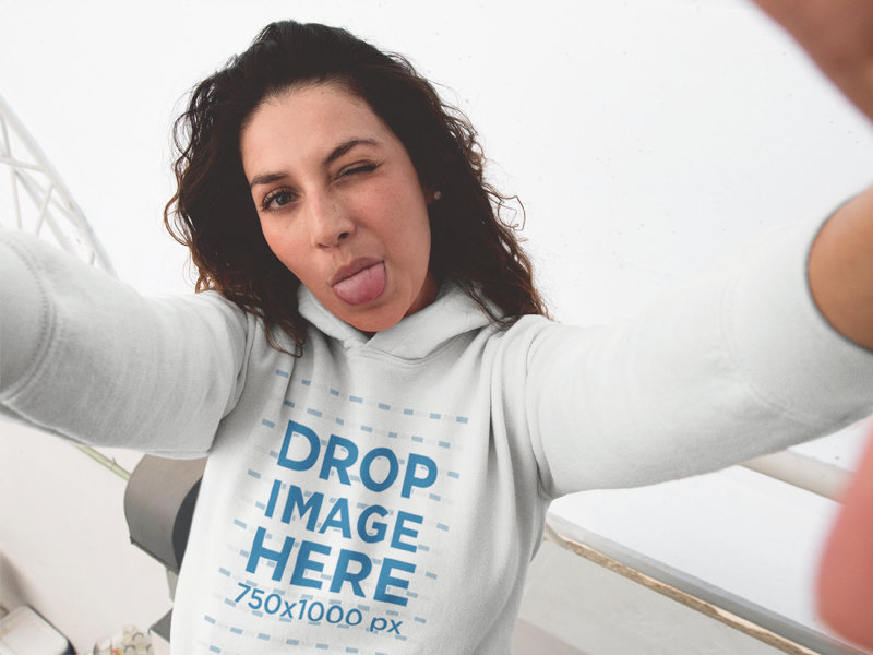 Lovely Young Woman Taking a Selfie with a Hoodie Mockup and her Tongue Out