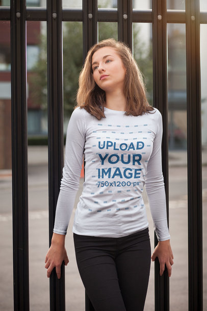 Long-Sleeve Tee Mockup of a Young Woman Posing by a Metal Fence