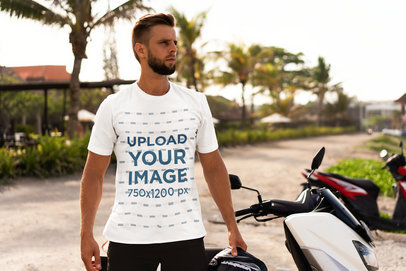 T-Shirt Mockup Featuring a Bearded Man with a Motorcycle on the Beach