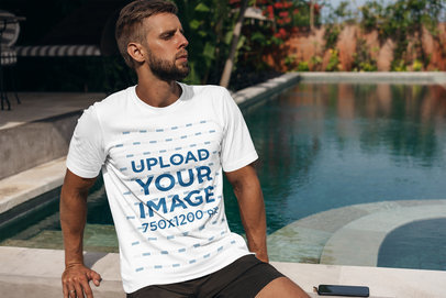 T-Shirt Mockup of a Bearded Man Sitting by a Pool