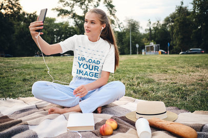 Tee Mockup of a Woman Doing a Video Call at an Outdoor Picnic