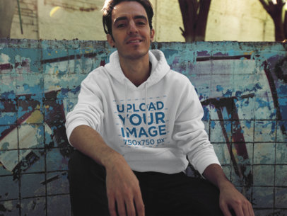 Cool Guy Sitting Against a Graffiti Wall Pullover Hoodie Mockup