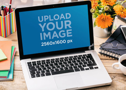 Mockup of a MacBook Pro Placed on a Wooden Desk by Colorful Flowers