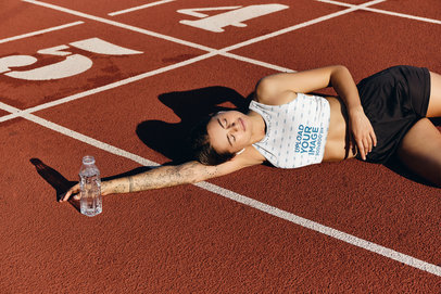 Sports Bra Mockup of a Woman Resting on a Running Track
