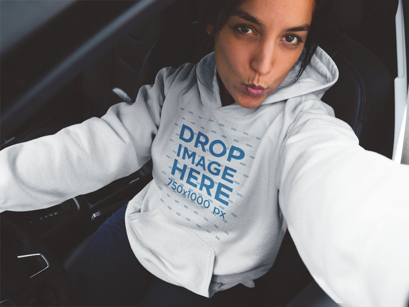 Young Woman in her Car Wearing a Pullover Hoodie and Taking a Selfie