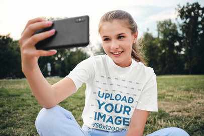 Tee Mockup of a Teenager Taking a Selfie at the Park