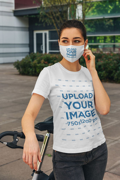Face Mask Mockup of a Young Woman Wearing a T-Shirt and Standing by a Bicycle 