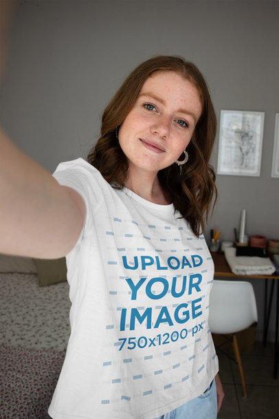 Selfie Mockup of a Woman Wearing a Round-Neck T-Shirt in Her Bedroom 