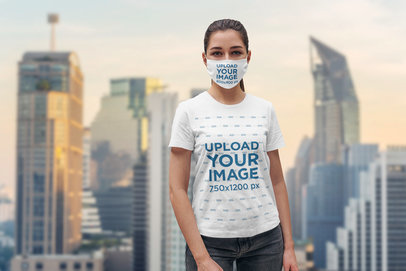 Face Mask Mockup of a Young Woman Wearing a T-Shirt Against a City Background 
