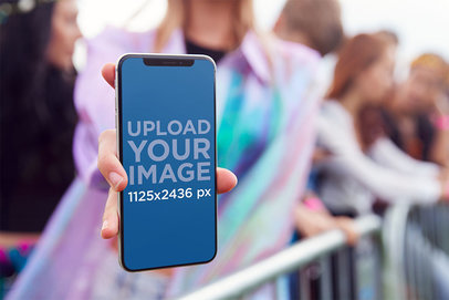 Mockup Featuring a Woman Holding an iPhone 11 Pro at a Concert 
