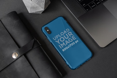 Mockup of a Clear Phone Case Placed Between a Computer and a Purse