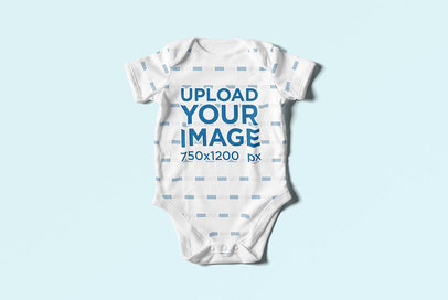 Mockup of a Baby Onesie Lying Flat on a Colored Surface