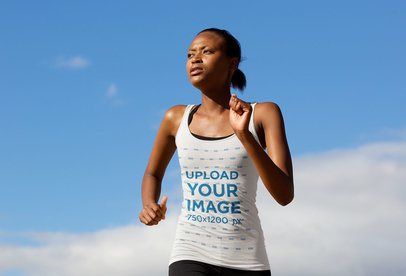 Tank Top Mockup of a Woman Running Against a Clear Blue Sky 