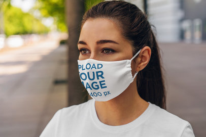 Mockup of a Woman Wearing a Customizable Face Mask in the City 