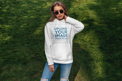 Mockup of a Woman With Sunglasses Wearing a Customizable Hoodie in a Garden 
