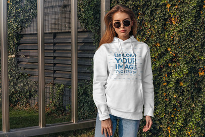 Hoodie Mockup of a Woman Standing by an Ivy-Covered Wall