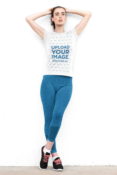 T-Shirt Mockup of a Woman in a Sporty Look Leaning on a White Wall 