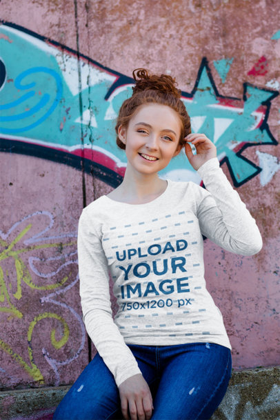 Heather Long Sleeve Tee Mockup of a Young Woman Sitting in Front of a Graffitied Wall
