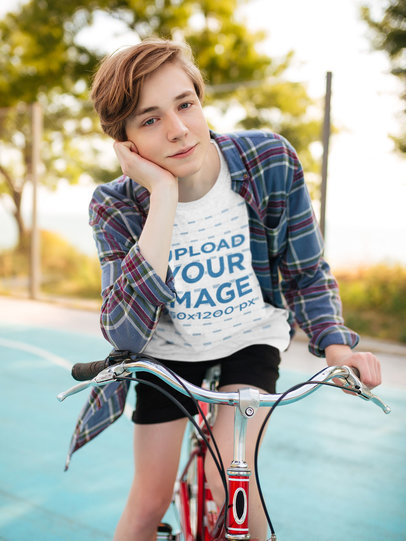 T-Shirt Mockup of a Young Man Posing on a Bike