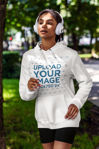 Mockup of a Woman with a Hoodie and Headphones Running on the Street