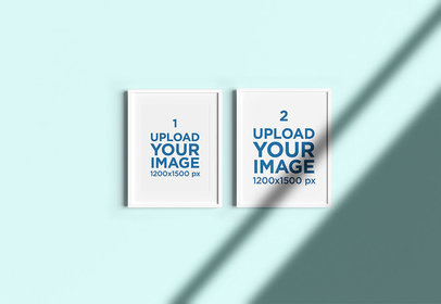 Mockup of Two Framed Art Prints Hanging on a Solid Color Wall 