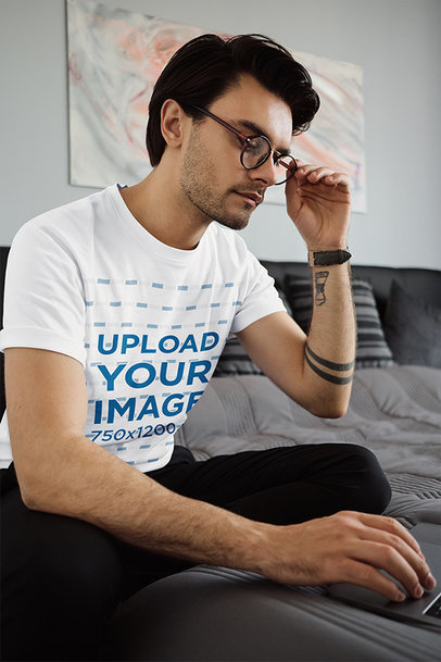 T-Shirt Mockup of a Man with Tattoos Working on the Bedroom