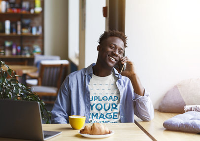 T-Shirt Mockup of a Happy Man Talking on the Phone at a Coffee Store 