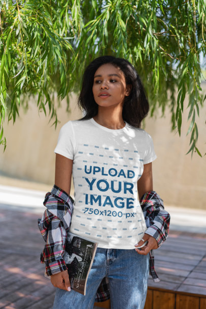 T-Shirt Mockup Featuring a Young Serious Woman Posing Under a Tree