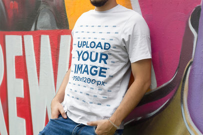 T-Shirt Mockup of a Man Leaning on a Wall with Graffiti