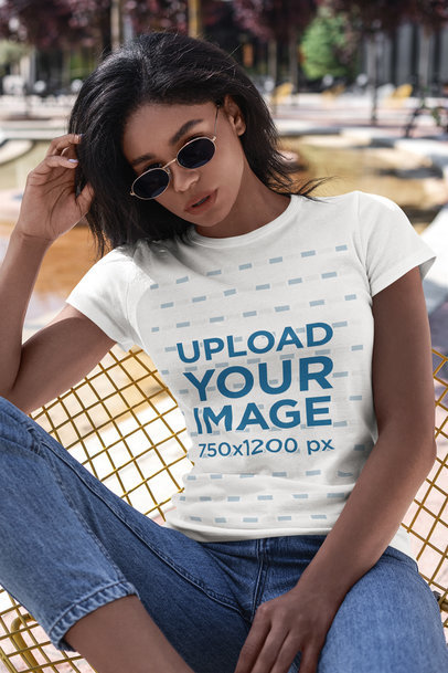 T-Shirt Mockup of a Young Woman Sitting on a Metallic Chair 