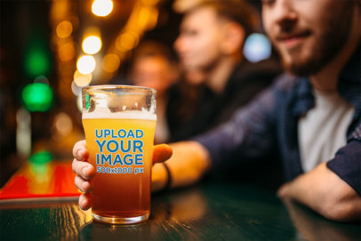 Mockup of a Man Holding a Beer Glass at a Bar